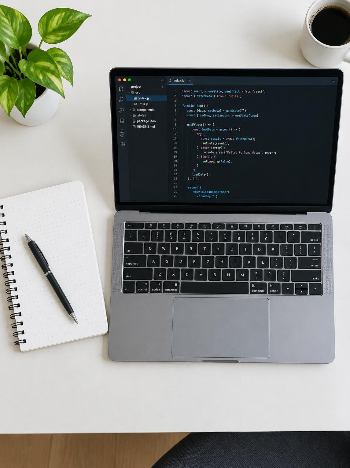 Laptop with code editor open beside a notebook